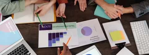 Mesa de trabajo donde un equipo de marketing analiza las métricas de una campaña publicitaria.