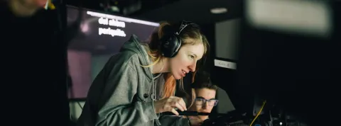 Operadora de cámara y otros técnicos graban una producción audiovisual.