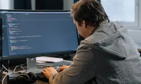 Hombre programando con una pantalla de ordenador