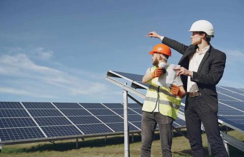 Dos hombres en un campo solar analizan la situación de la instalación de placas solares.