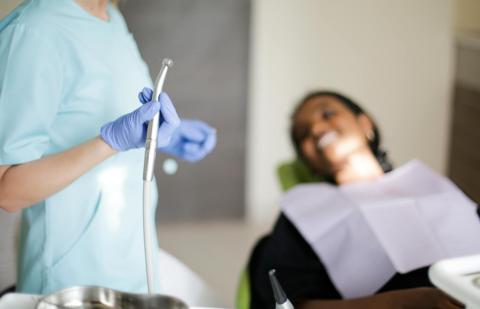 Dentista realiza un curetaje dental en una paciente.