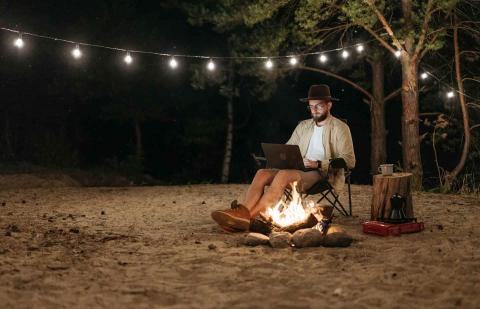 Un hombre estudia de noche en un camping.