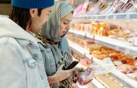 Dos jovenes miran la etiqueta nutricional de un producto en el supermercado.