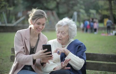 Mujer enseñando tecnologia a una señora mayor