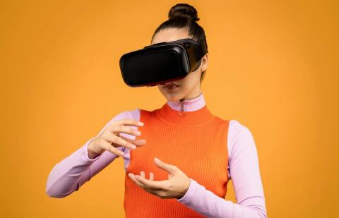 Una mujer con gafas de realidad virtual interactúa en el metaverso.