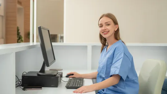 Mujer en su mesa de trabajo, trabaja con ordenador en administración sanitaria