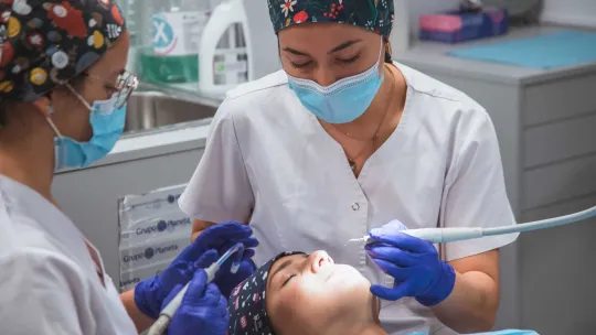 Higienista Bucodental y odontóloga realizan un tratamiento en una clínica dental.