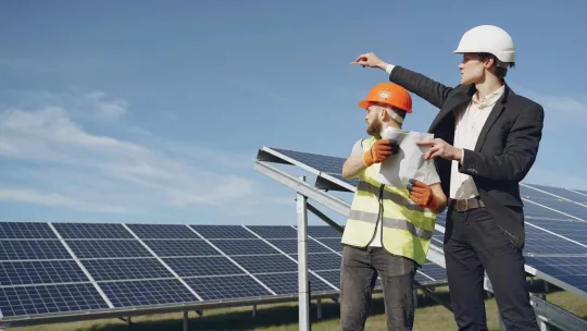 Dos hombres en un campo solar analizan la situación de la instalación de placas solares.