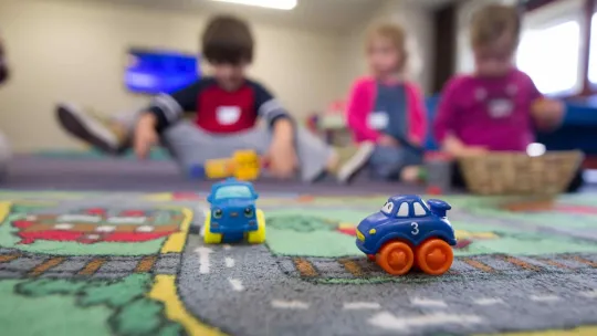 Niños de educación infantil jugando en el suelo con coches de juguetes