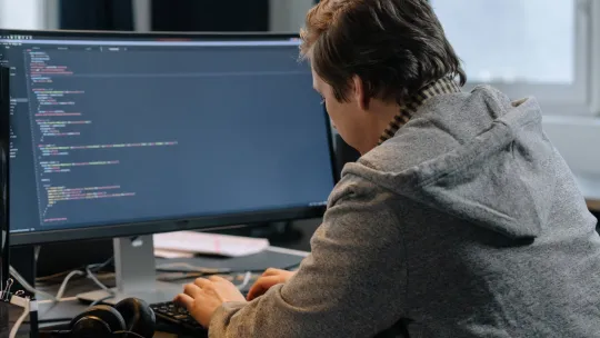 Hombre programando con una pantalla de ordenador