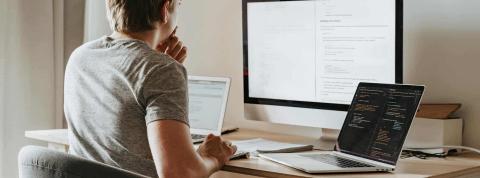 Un hombre con un monitor y dos portátiles, utiliza una API.