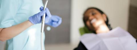 Dentista realiza un curetaje dental en una paciente.