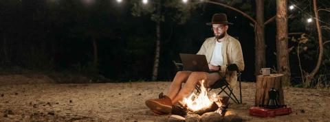 Un hombre estudia de noche en un camping.