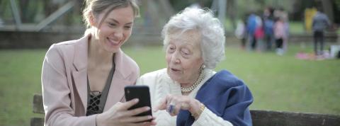 Mujer enseñando tecnologia a una señora mayor