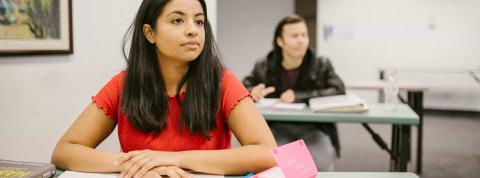 Chica joven atendiendo en clase con un cuaderno en la mesa